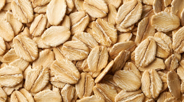 A top view macro photo of raw rolled oats grains packed closely together displaying natural oat flake texture and pattern.