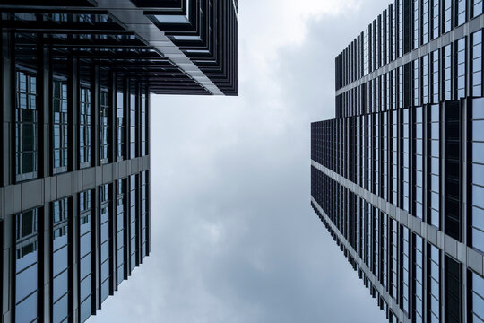 Low angle view between offices and buildings with vertical architecture and sky in Wola, Warsaw, Poland emphasizing perspective through the frame.