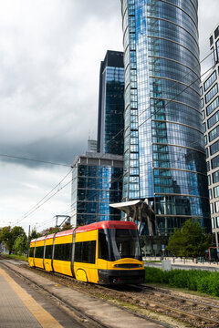 Warsaw tram approaching along tracks between skyscrapers in Wola business district, Warsaw, Poland creating an urban transport perspective.