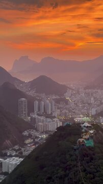 Sunset panorama from Morro da Urca overlooking Rio de Janeiro with the Sugarloaf Cable Car descending above the city.