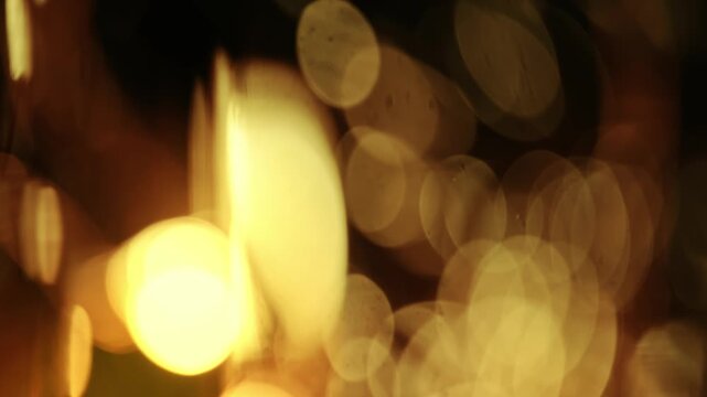 Macro close-up shot of glowing warm fairy lights producing soft golden bokeh orbs against a dark background.