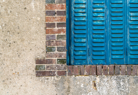 Blue wooden shutters, brick frame and weathered wall, Yonne, France