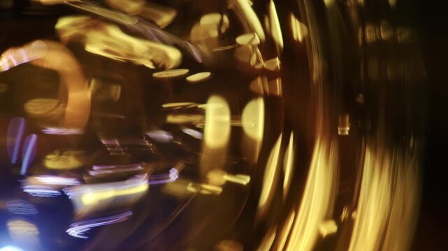 Macro shot of dynamic golden light streaks and curved glass refraction with glowing bokeh against a dark background.
