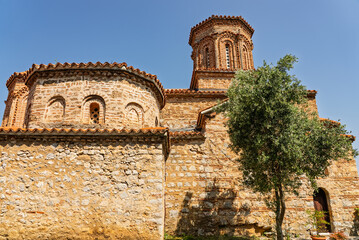 Fototapeta premium St Naum Monastery on the shore of Lake Ohrid in North Macedonia, with beautiful beaches, crystal clear blue water and scenic mountain landscape surrounding the historic religious site.