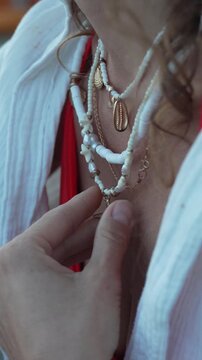 Styling beaded shell necklaces with starfish pendants against a white shirt. Macro close-up shot.