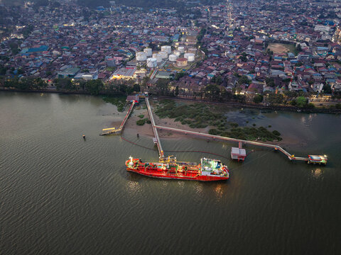 Aerial view of PT. Pertamina TBBM Samarinda fuel storage facility with a red tanker ship docked at the pier on the Mahakam River in Samarinda, Kalimantan Timur, Indonesia.