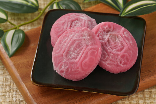 Traditional pink red turtle rice cake on woven grass mat background.