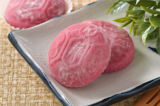 Traditional pink red turtle rice cake on woven grass mat background.