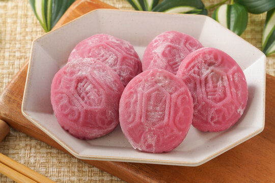 Traditional pink red turtle rice cake on woven grass mat background.