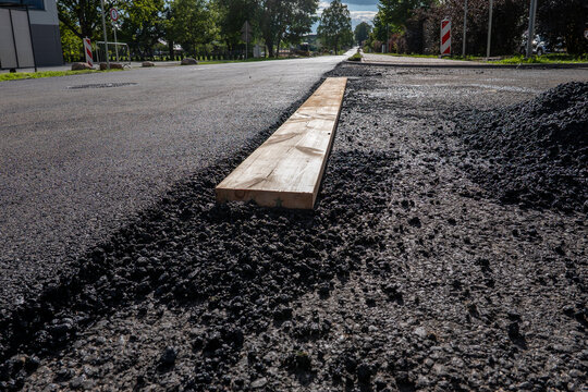 Fresh Asphalt Road Construction with Wooden Divider and Work Zone Signs