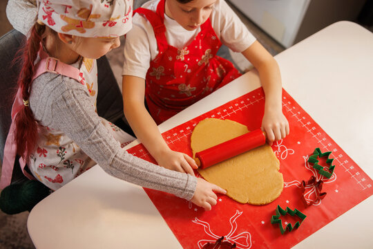 Siblings preparing festive homemade cookies together as part of a Christmas tradition.