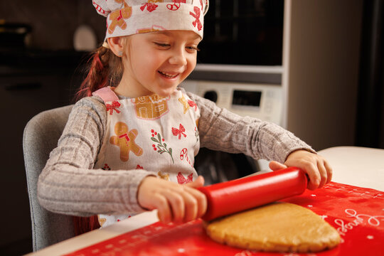 Smiling girl rolling out cookie dough during Christmas baking at home.