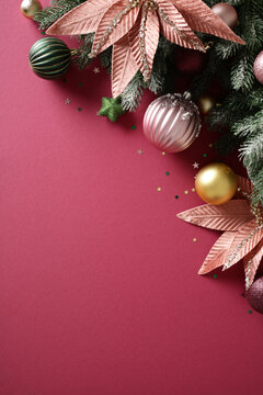 Christmas background with baubles and poinsettia on pink