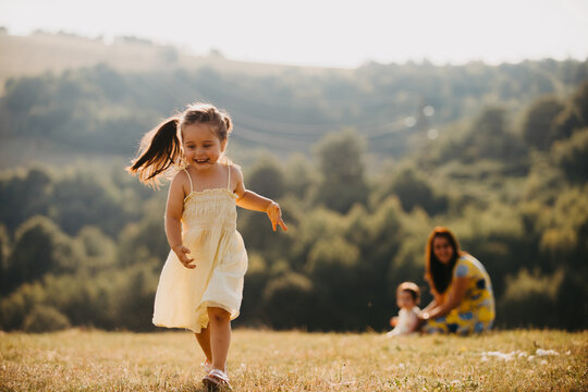Happy Little Girl Running in Summer Meadow With Mother and Baby in Countryside Afternoon