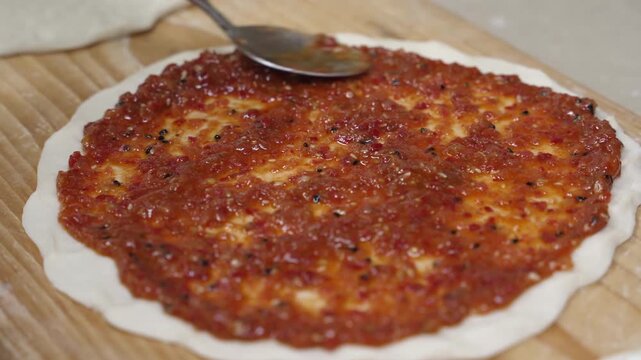 Chef spreading red tomato sauce over flatbread dough on a wooden board pizza food kitchen cooking bread pizza food kitchen cooking bread