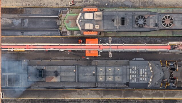 Aerial view of two freight locomotives parked in a rail yard with a worker in an orange vest standing between them in Denver, Colorado, United States.