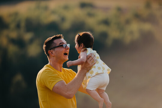 Father Playing With Baby Outdoors At Sunset Smiling Parent And Child Bonding In Nature
