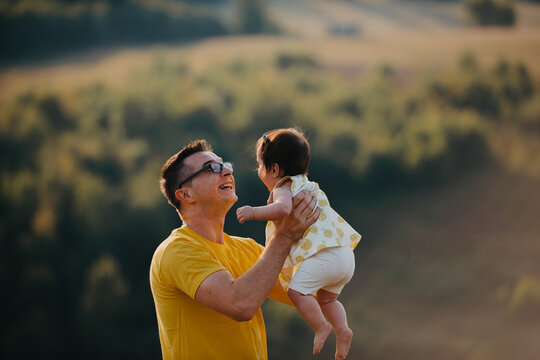 Father Lifting Baby Daughter Outdoors at Golden Hour &mdash; Joyful Family Bonding and Parent Love