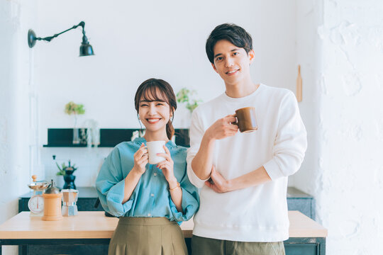 コーヒーカップを持つ若い夫婦 