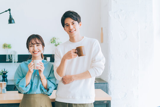 コーヒーカップを持つ若い夫婦 