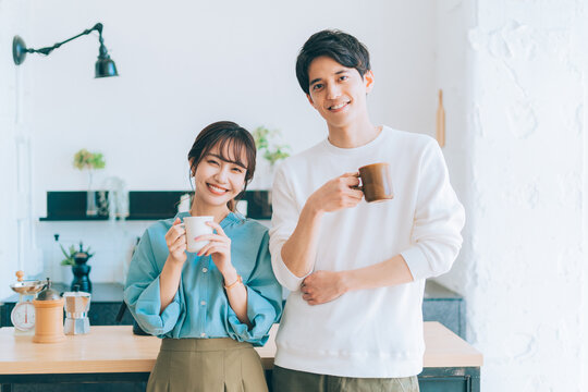 コーヒーカップを持つ若い夫婦 