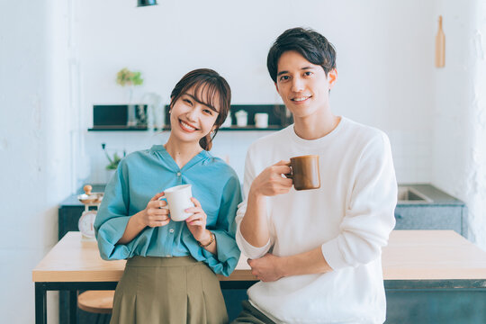 コーヒーカップを持つ若い夫婦 