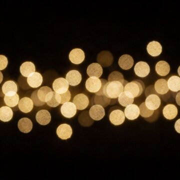 Golden bokeh lights on a black background creating a festive and elegant abstract pattern