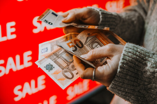 Person holding euro banknotes during sale shopping.