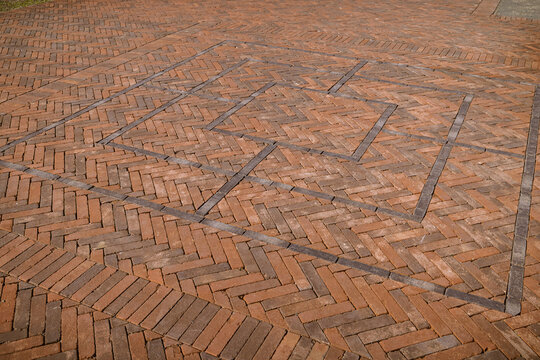 A detailed view of a classic red brick terrace patio featuring a decorative herringbone pattern