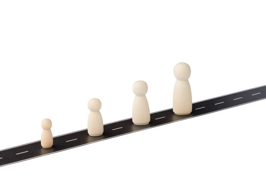 Wooden figures of different sizes standing on a road on white background