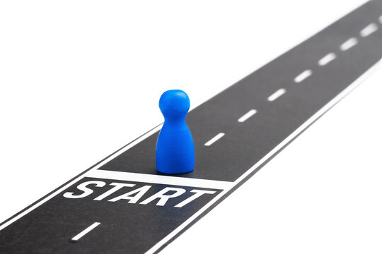 Blue pawn figure standing on a road start line isolated on white background.