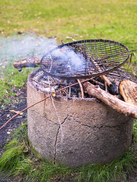 Smoky campfire with metal grate on concrete fire pit. outdoor
