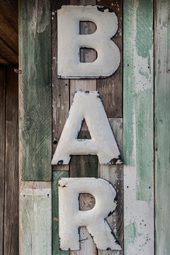 Schriftzug Bar aus Emaille-Blech an einer Holzfassade