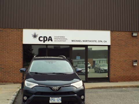 Gloucester, Ontario, Canada &ndash; July 27, 2026: The "Michael Northcote CPA" storefront features an overhead signage board, glass double doors, brick exterior, and a parked dark SUV car at 5370 Canotek Rd