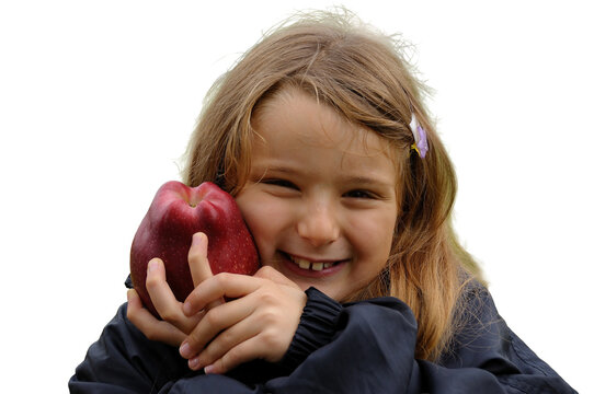 A little girl, isolated against a transparent background, with a red apple pressed against her cheek, smiling happily.