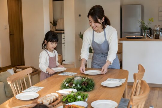 食卓に皿を並べる母と子