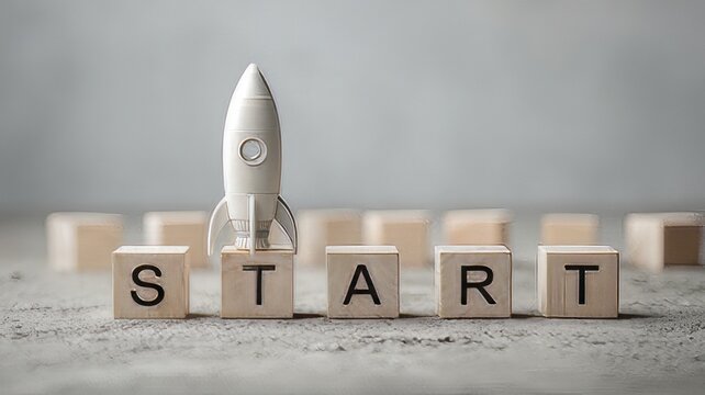 Wooden blocks spelling the word START next to a small, stylized toy rocket. Beginning of a venture. motivational message about launching new projects or businesses.