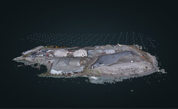 Aerial view of an industrial site with gravel piles and heavy machinery on a small landmass in Richmond, British Columbia, Canada.