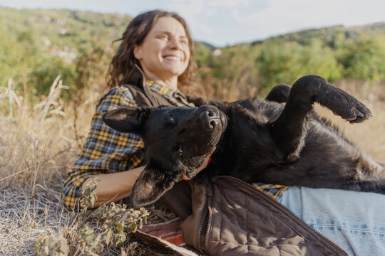 Funny black dog lying upside down on its owner's lap during an outdoor walk