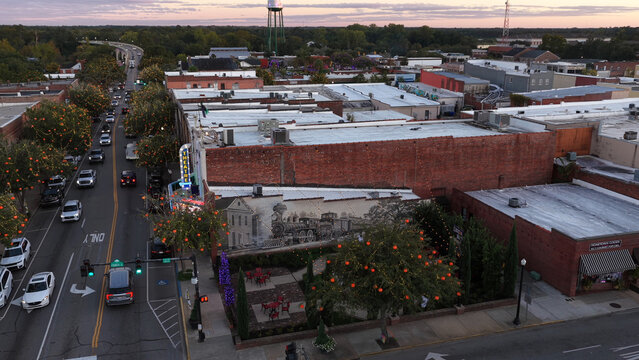 Aerial view of the historic downtown area of Conway featuring a large mural on a brick building, a theater, and tree-lined streets at sunset in Conway, South Carolina, United States.