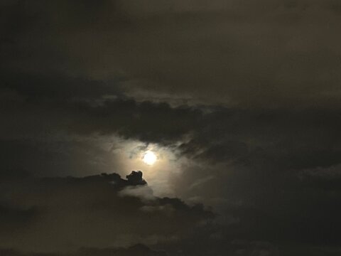 Moon shining through dramatic clouds at night