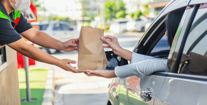 Delivery person hands food to customer through car window