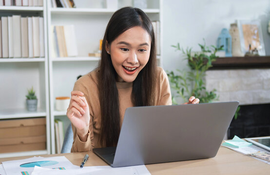 Young woman smiles brightly while using laptop at home