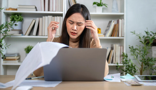 Woman stresses at desk, hands on forehead