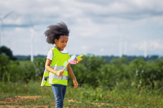 Young girl walks through green field, holding colorful toy