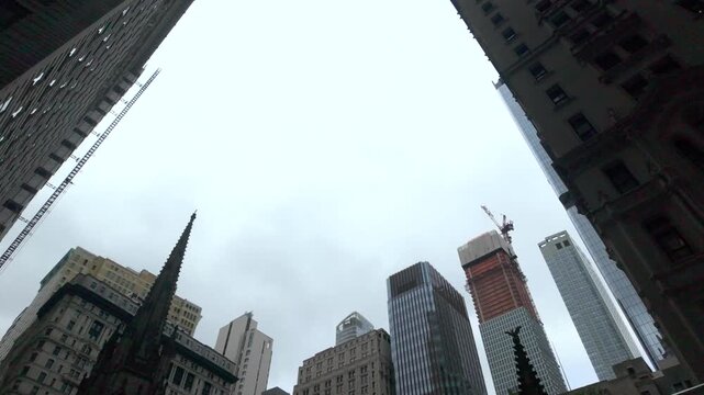 Financial district skyscrapers and trinity church on a cloudy day in lower manhattan, new york city, featuring modern architecture, iconic landmarks, and new construction sites