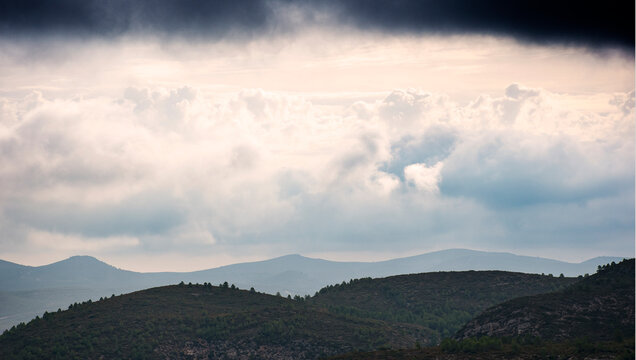 Nubes dram&aacute;ticas sobre monta&ntilde;as y colinas bajo cielo tormentoso