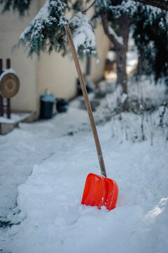 Snow shovel stuck in deep snow in the yard of a country house.