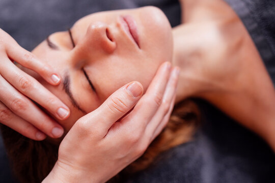Female receiving relaxing facial massage in a serene spa environment, showcasing skilled hands and tranquil ambiance, promoting wellness and self-care practices