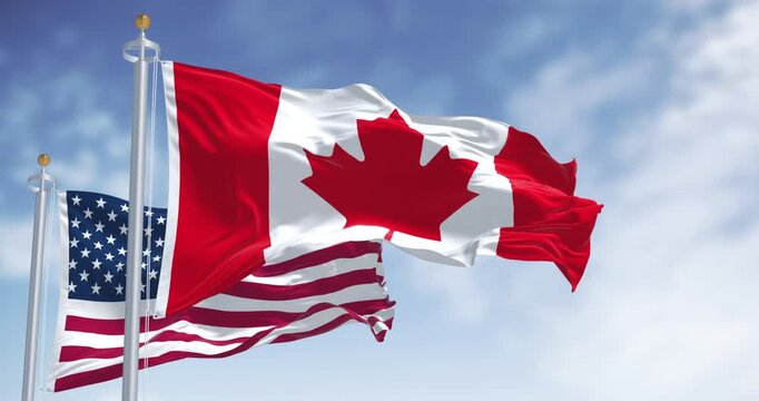 Canada and american national flags waving in the wind on a clear day